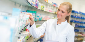 Junge Apothekerin sucht Medikamente aus einem Regal