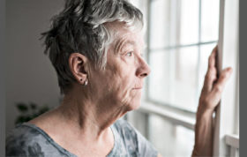 Seniorin schaut aus Fenster