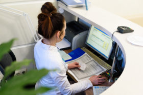 Arzthelferin sitzt am Computer der Anmeldung